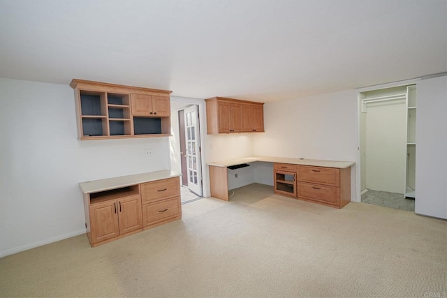 unfurnished office featuring built in desk and light carpet