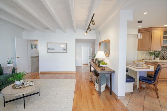 living room featuring track lighting, light wood-type flooring, and beam ceiling