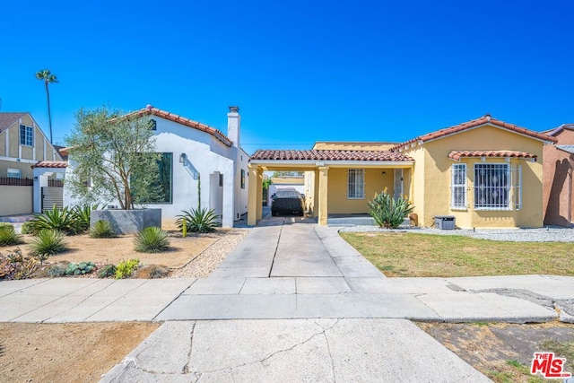 mediterranean / spanish home with a carport, a front yard, and a garage