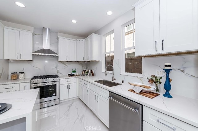 kitchen featuring white cabinets, sink, stainless steel appliances, and wall chimney range hood