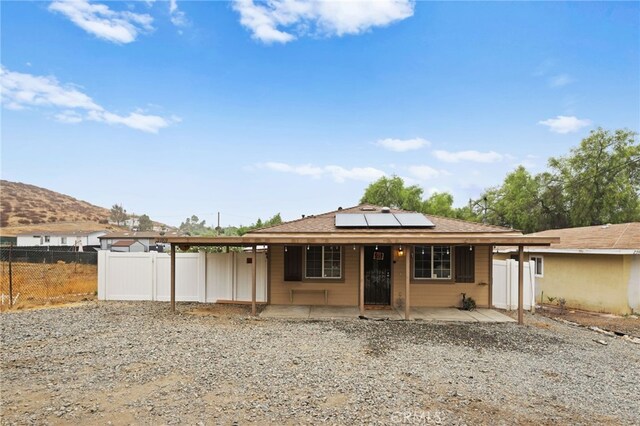 rear view of property featuring a patio area and solar panels