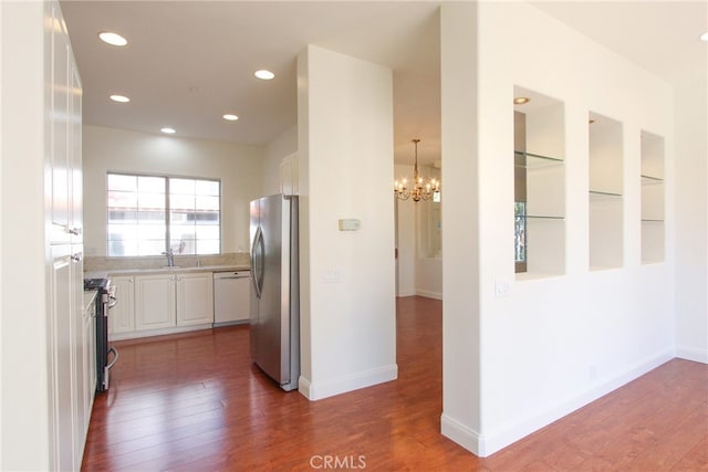 kitchen featuring white cabinetry, stainless steel appliances, hanging light fixtures, and dark wood-type flooring