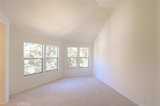 carpeted spare room featuring vaulted ceiling