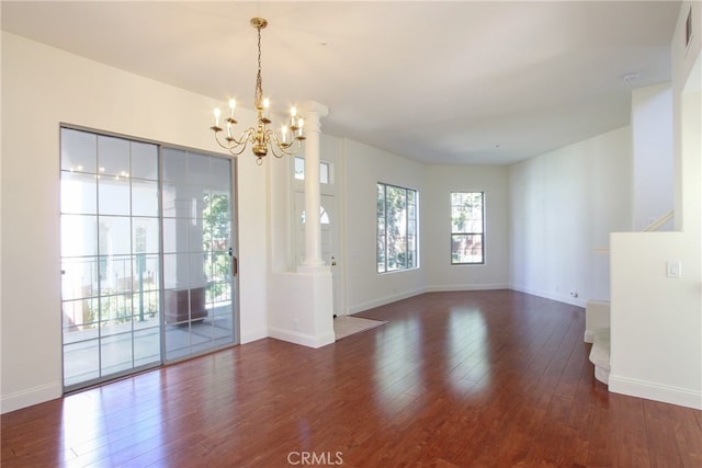 interior space with a notable chandelier, ornate columns, and dark wood-type flooring