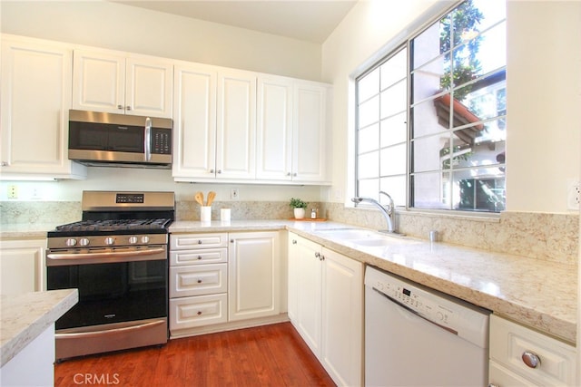 kitchen with sink, light stone countertops, appliances with stainless steel finishes, dark hardwood / wood-style flooring, and white cabinetry