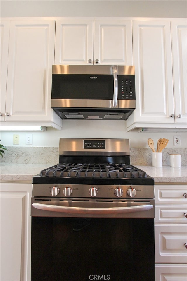 kitchen featuring white cabinets, appliances with stainless steel finishes, and light stone countertops