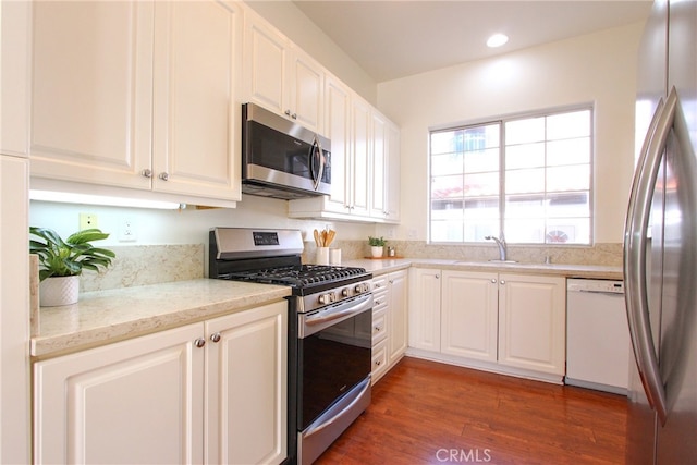 kitchen featuring white cabinetry, sink, dark wood-type flooring, light stone counters, and appliances with stainless steel finishes