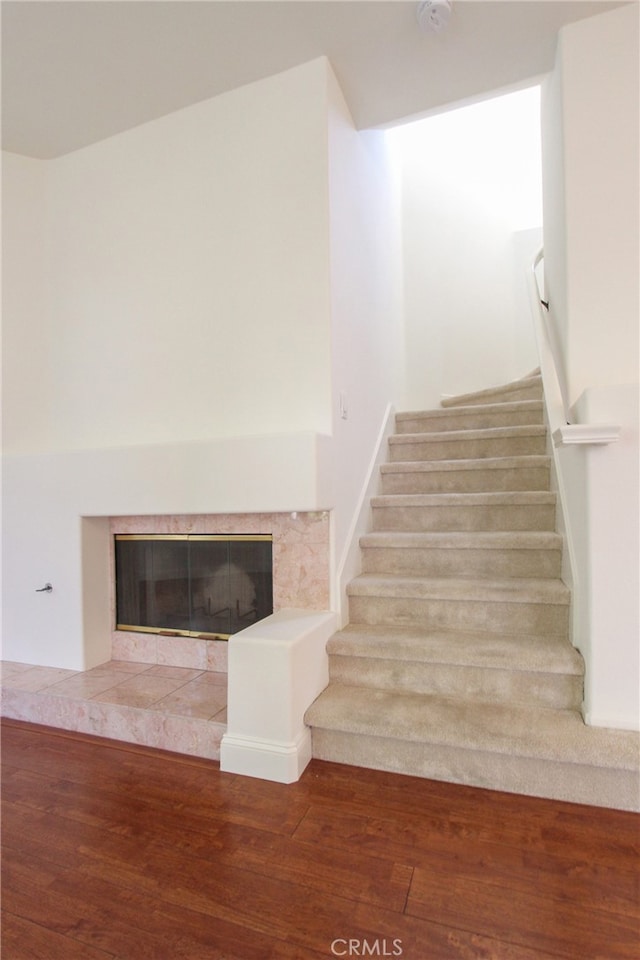 staircase with a tile fireplace and hardwood / wood-style floors