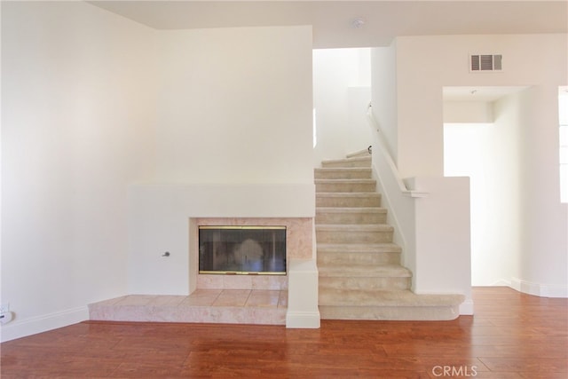 stairway featuring hardwood / wood-style flooring and a tiled fireplace