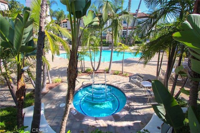 view of swimming pool featuring a community hot tub and a patio area