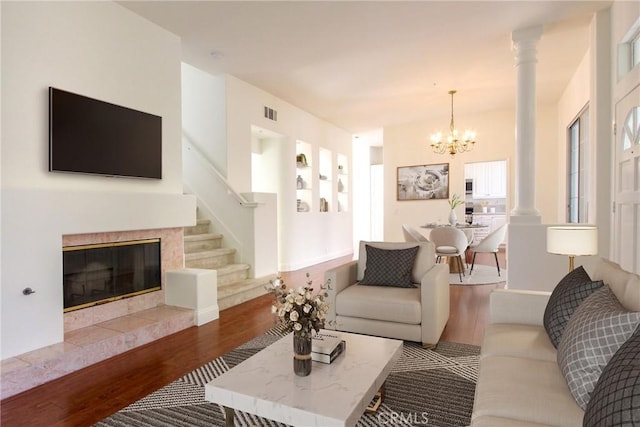 living room featuring a tiled fireplace, an inviting chandelier, and hardwood / wood-style flooring