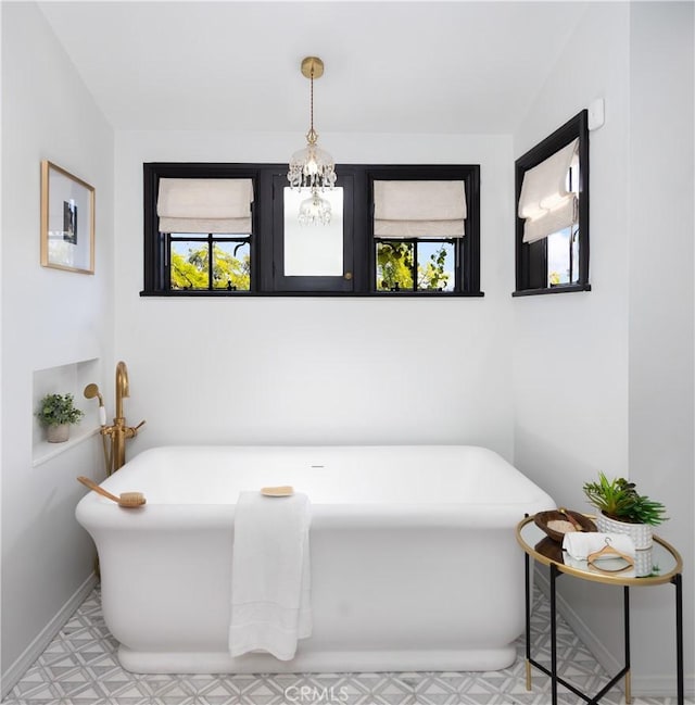 bathroom with a washtub and a notable chandelier