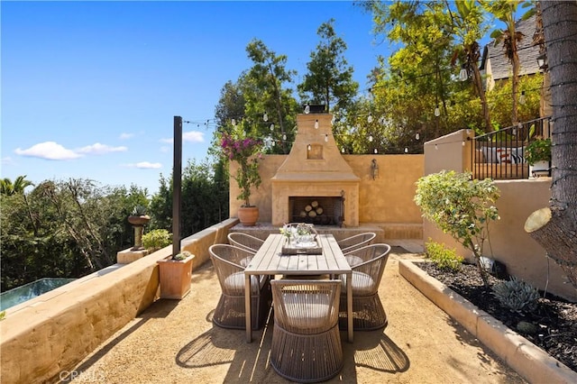 view of patio featuring exterior fireplace and outdoor dining space