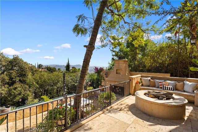 view of patio / terrace with a fire pit, a balcony, and an outdoor fireplace