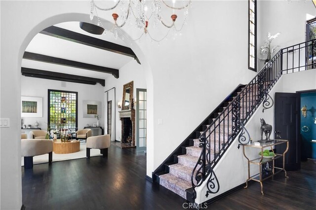 stairs featuring a towering ceiling, wood-type flooring, and beamed ceiling