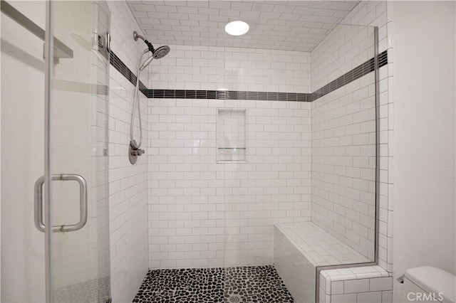 bathroom featuring a shower with door and toilet