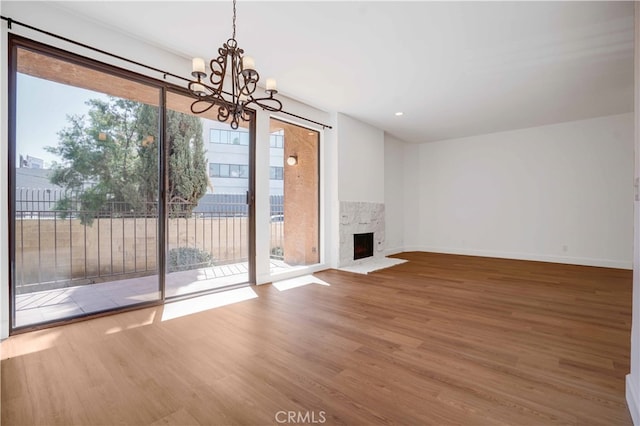 unfurnished living room with a fireplace, wood-type flooring, a chandelier, and a wealth of natural light