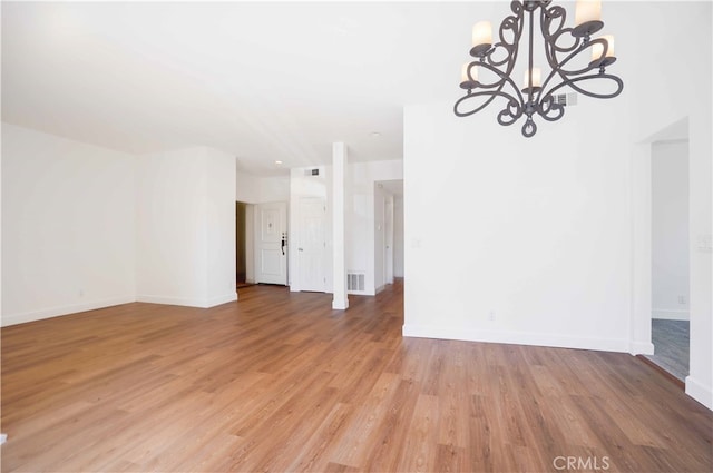 empty room featuring light hardwood / wood-style floors and a chandelier