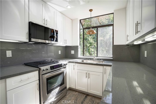 kitchen featuring pendant lighting, dark wood-type flooring, sink, white cabinets, and appliances with stainless steel finishes