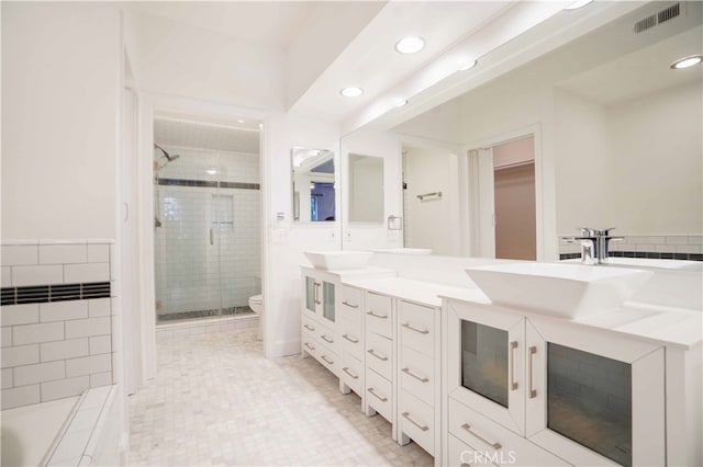 bathroom featuring a shower with shower door, vanity, and toilet