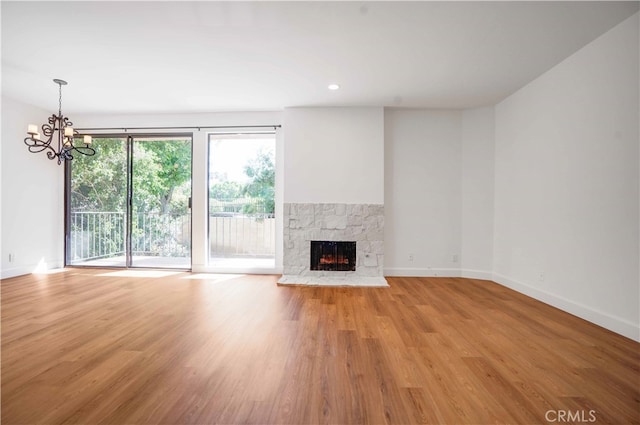 unfurnished living room featuring a notable chandelier, a fireplace, and light hardwood / wood-style floors