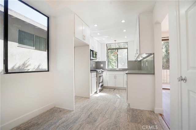 kitchen with tasteful backsplash, appliances with stainless steel finishes, and white cabinetry