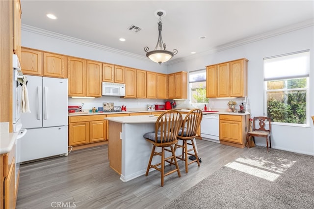 kitchen with ornamental molding, white appliances, wood-type flooring, decorative light fixtures, and a center island