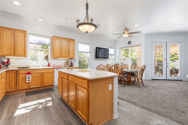 kitchen featuring hanging light fixtures, ornamental molding, a healthy amount of sunlight, and a center island