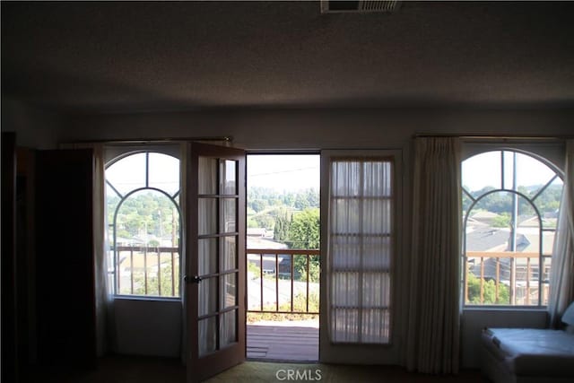 doorway to outside with plenty of natural light and a textured ceiling