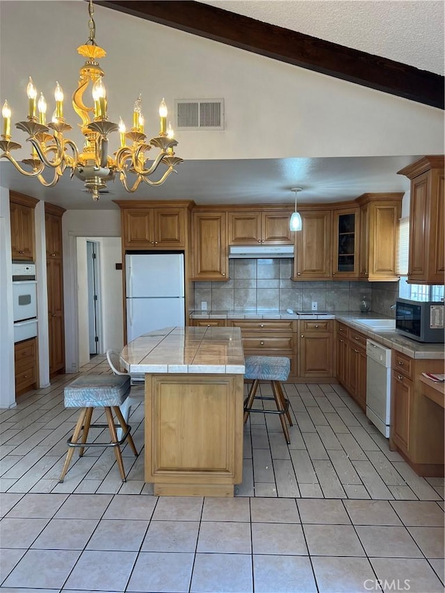 kitchen featuring lofted ceiling with beams, light tile patterned floors, white appliances, and decorative light fixtures