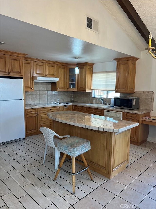 kitchen featuring sink, white appliances, a center island, tile counters, and decorative backsplash