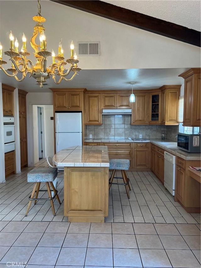 kitchen featuring pendant lighting, light tile patterned floors, white appliances, a center island, and lofted ceiling with beams