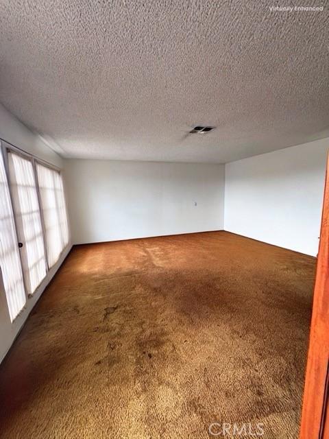 spare room featuring carpet and a textured ceiling