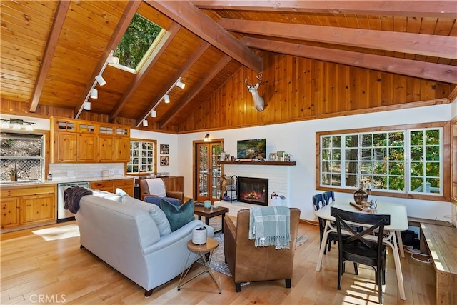 living room with beamed ceiling, light wood-type flooring, and plenty of natural light