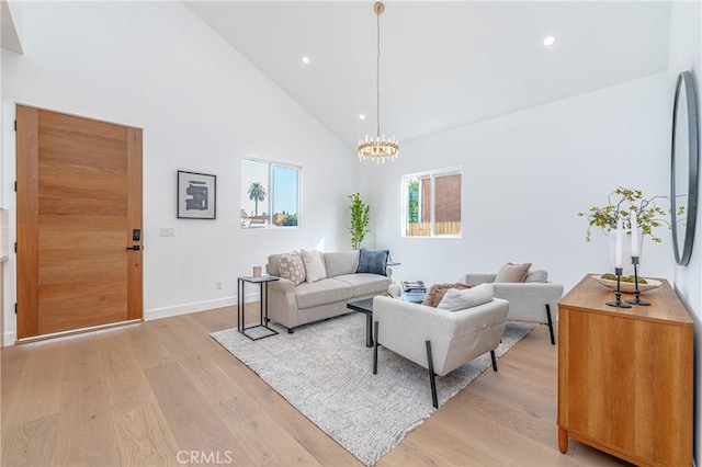 living room with a notable chandelier, light hardwood / wood-style floors, and high vaulted ceiling