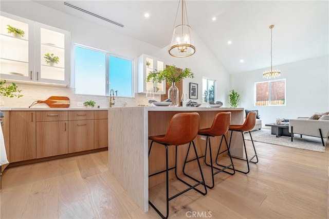 kitchen with a kitchen island, tasteful backsplash, light hardwood / wood-style flooring, and a chandelier