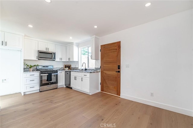 kitchen featuring white cabinets, stainless steel appliances, light hardwood / wood-style floors, and sink