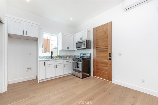 kitchen featuring white cabinetry, stainless steel appliances, a wall mounted air conditioner, and light hardwood / wood-style floors