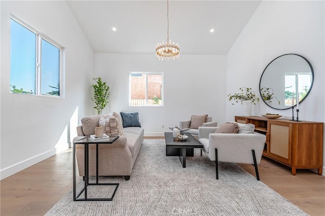 living room featuring high vaulted ceiling, light hardwood / wood-style flooring, a wealth of natural light, and a notable chandelier