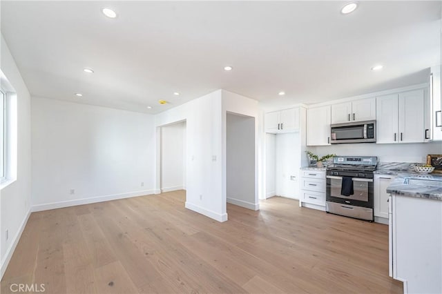 kitchen featuring white cabinets, light stone countertops, stainless steel appliances, and light hardwood / wood-style flooring