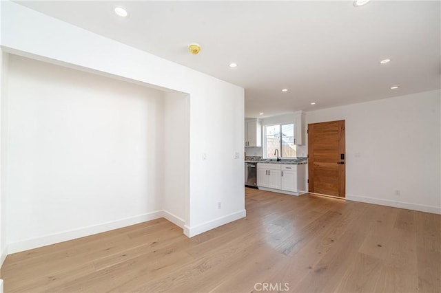 unfurnished living room featuring sink and light hardwood / wood-style floors