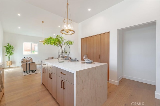 kitchen featuring light brown cabinets, a center island, light hardwood / wood-style floors, and light stone counters