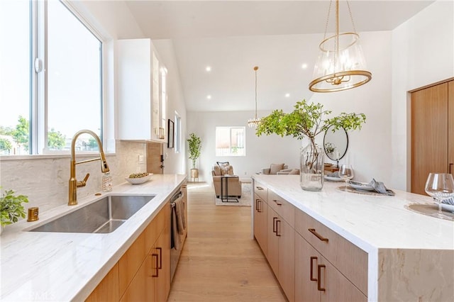 kitchen with pendant lighting, light hardwood / wood-style floors, a healthy amount of sunlight, and sink