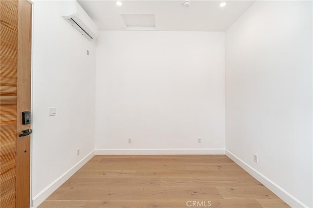 unfurnished room with a wall unit AC and light hardwood / wood-style flooring