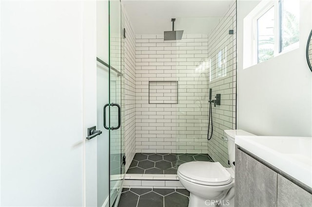 bathroom featuring tile patterned floors, vanity, toilet, and a shower with shower door