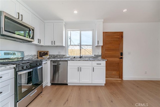 kitchen with white cabinets, sink, light hardwood / wood-style flooring, light stone countertops, and stainless steel appliances