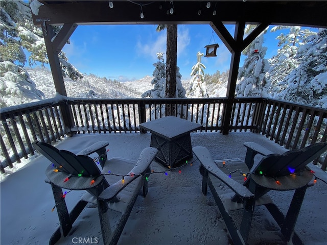 snow covered patio with a mountain view