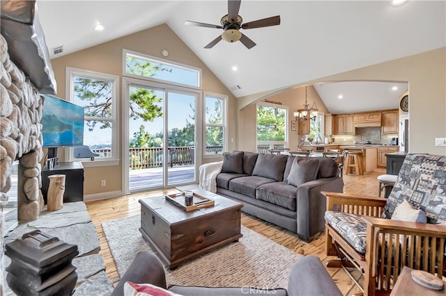 living room featuring ceiling fan with notable chandelier, light hardwood / wood-style floors, high vaulted ceiling, and a healthy amount of sunlight