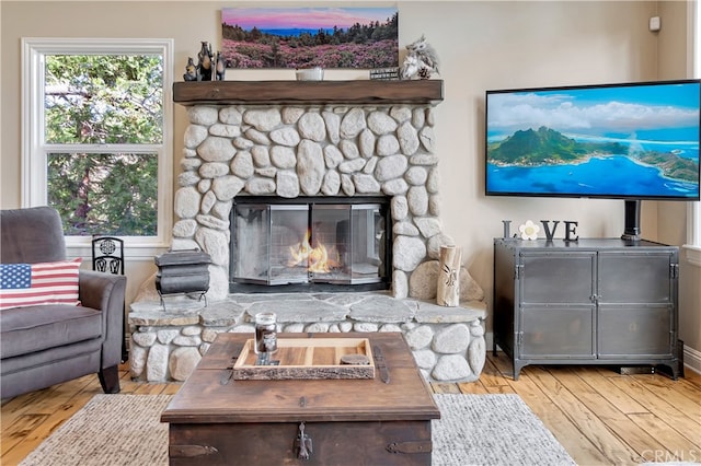 living room featuring a stone fireplace and light hardwood / wood-style floors