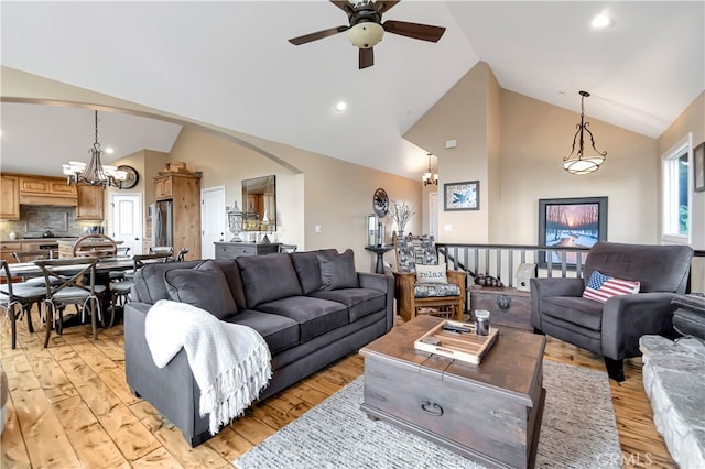 living room featuring ceiling fan with notable chandelier, light hardwood / wood-style floors, and high vaulted ceiling